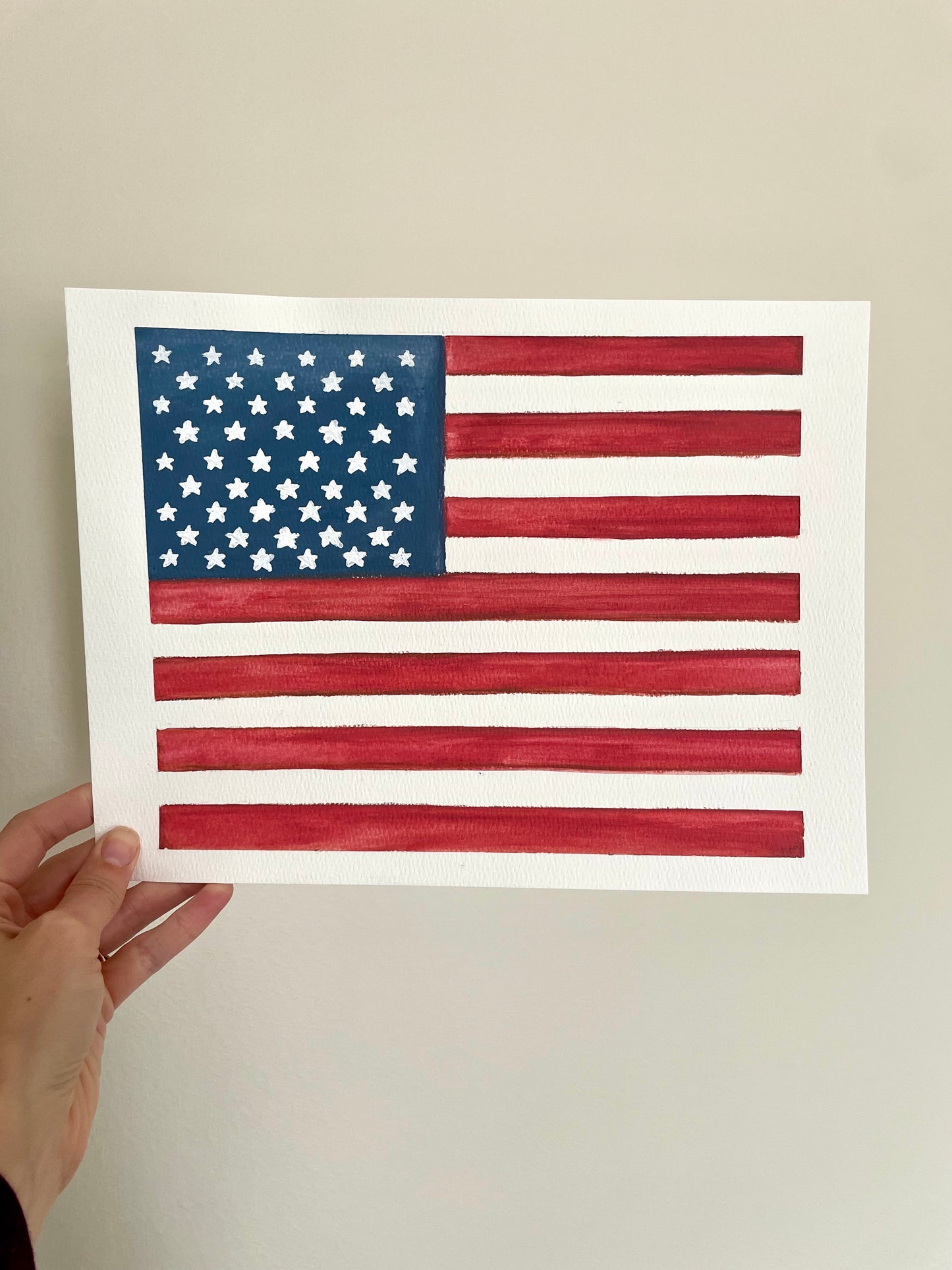 Hand holding a hand painted American flag against a plain background for sale home decor NicoleMayLesher.com