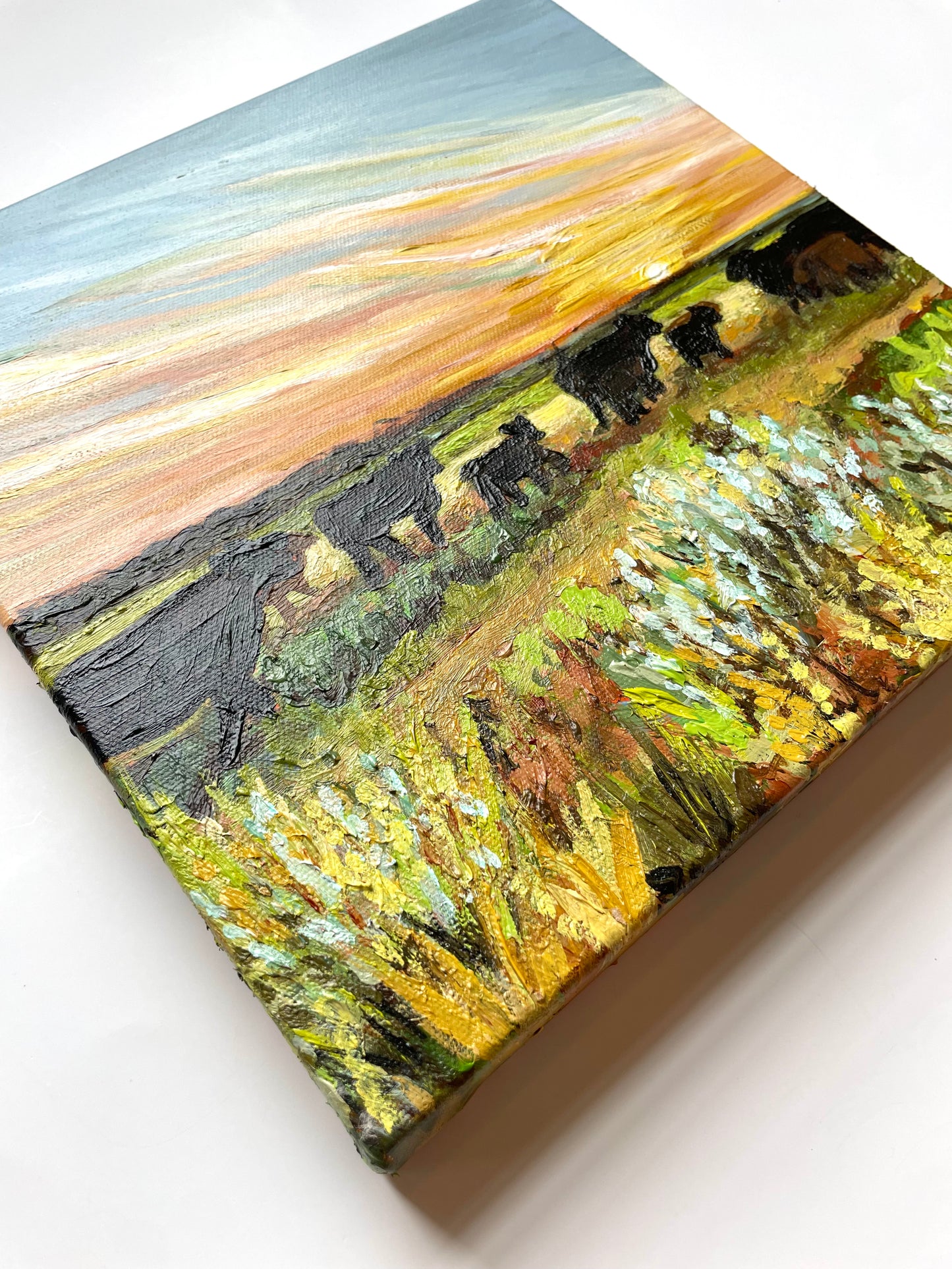 Painting of cows in a field with a sunset sky
