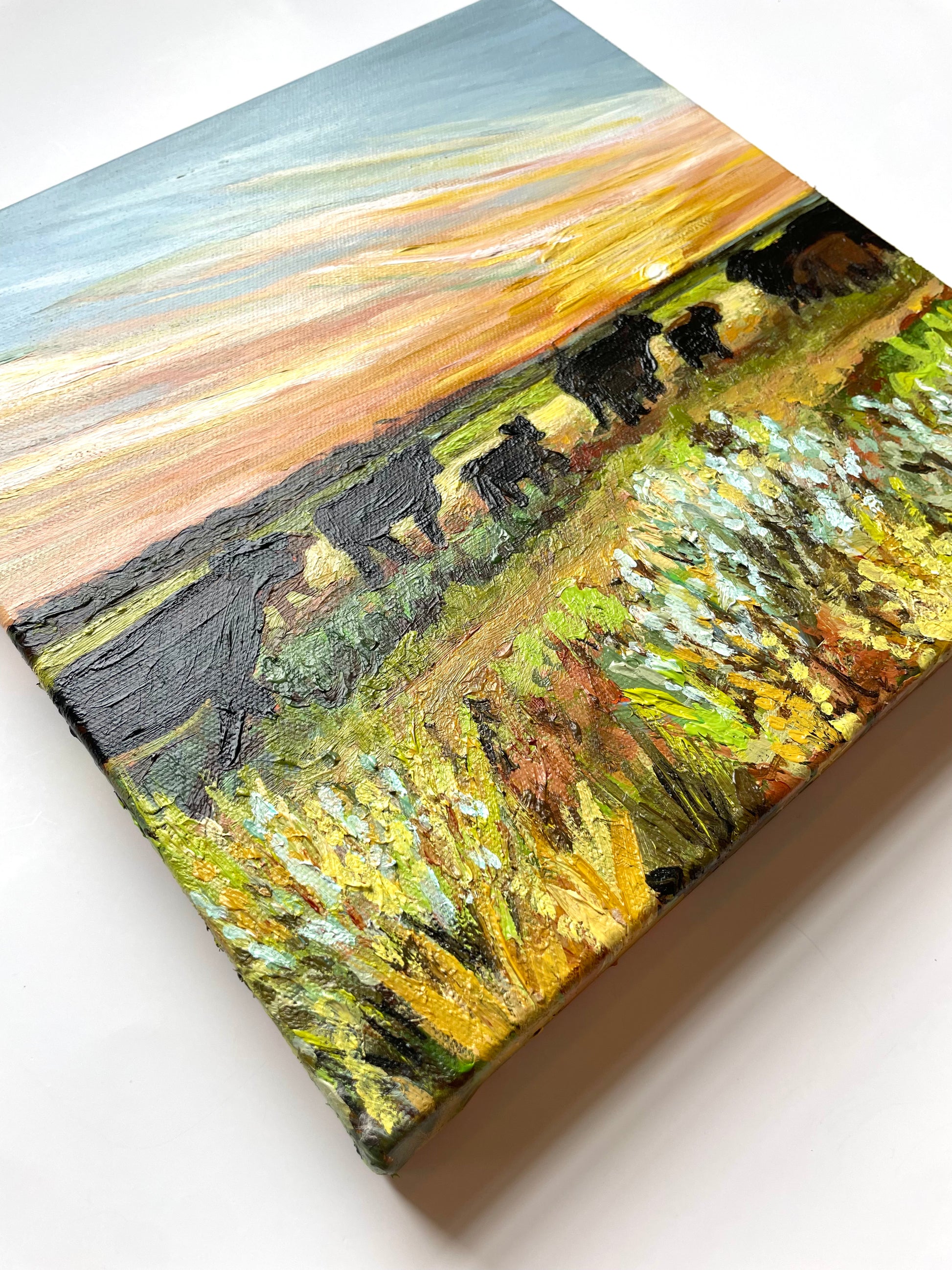 Painting of cows in a field with a sunset sky