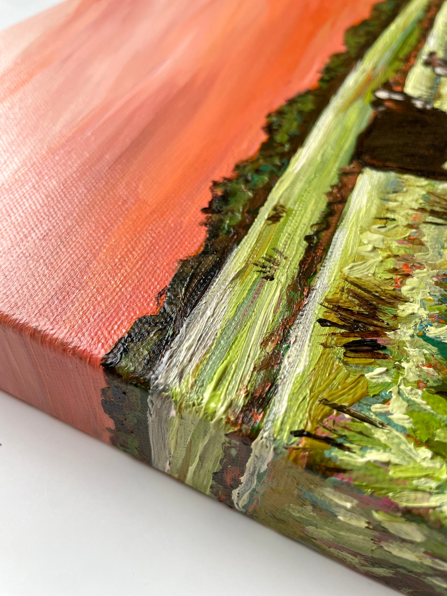 Close-up of a textured painting with green, black, brown and orange colors