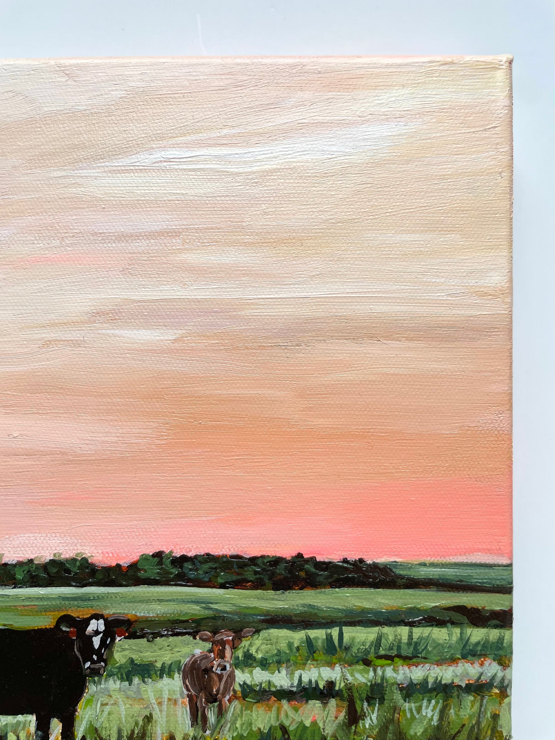 Painting of cows in a field with a pink sky