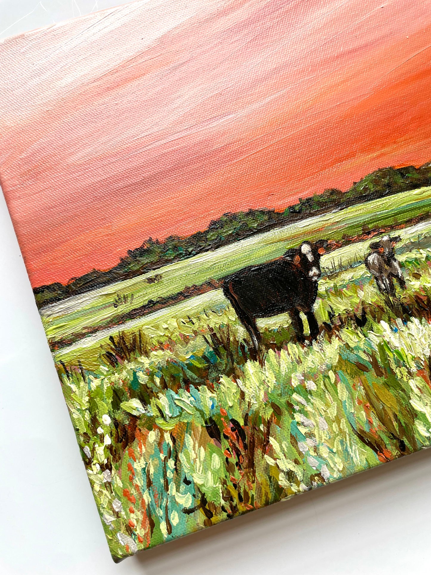 Painting of a cow in a field with an orange sunset sky