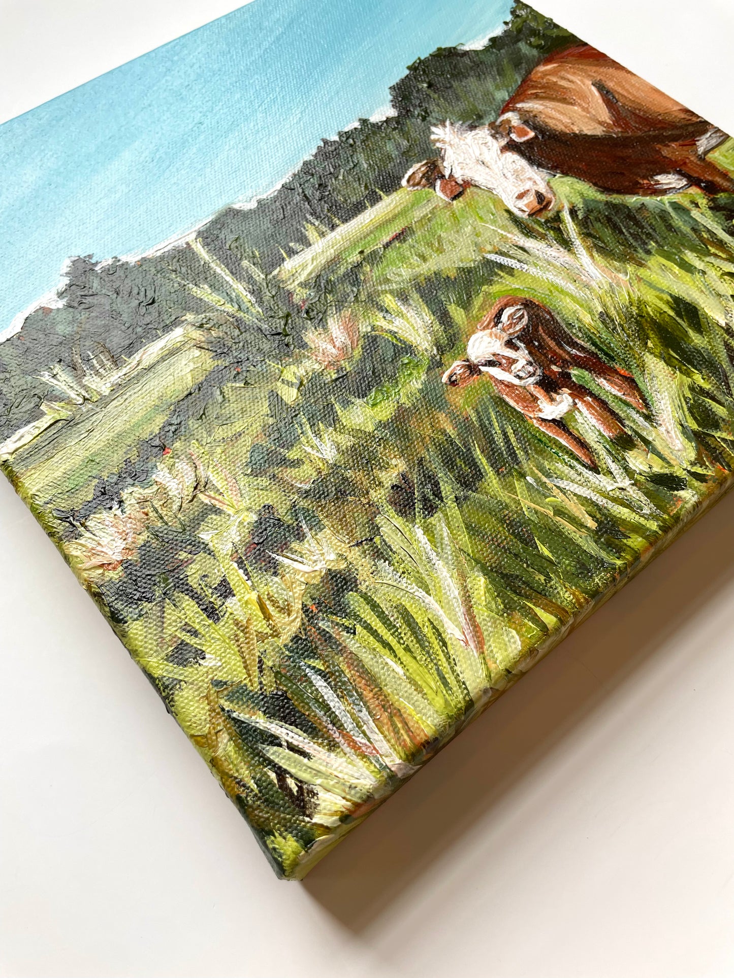 Canvas painting of cows in a field with a blue sky