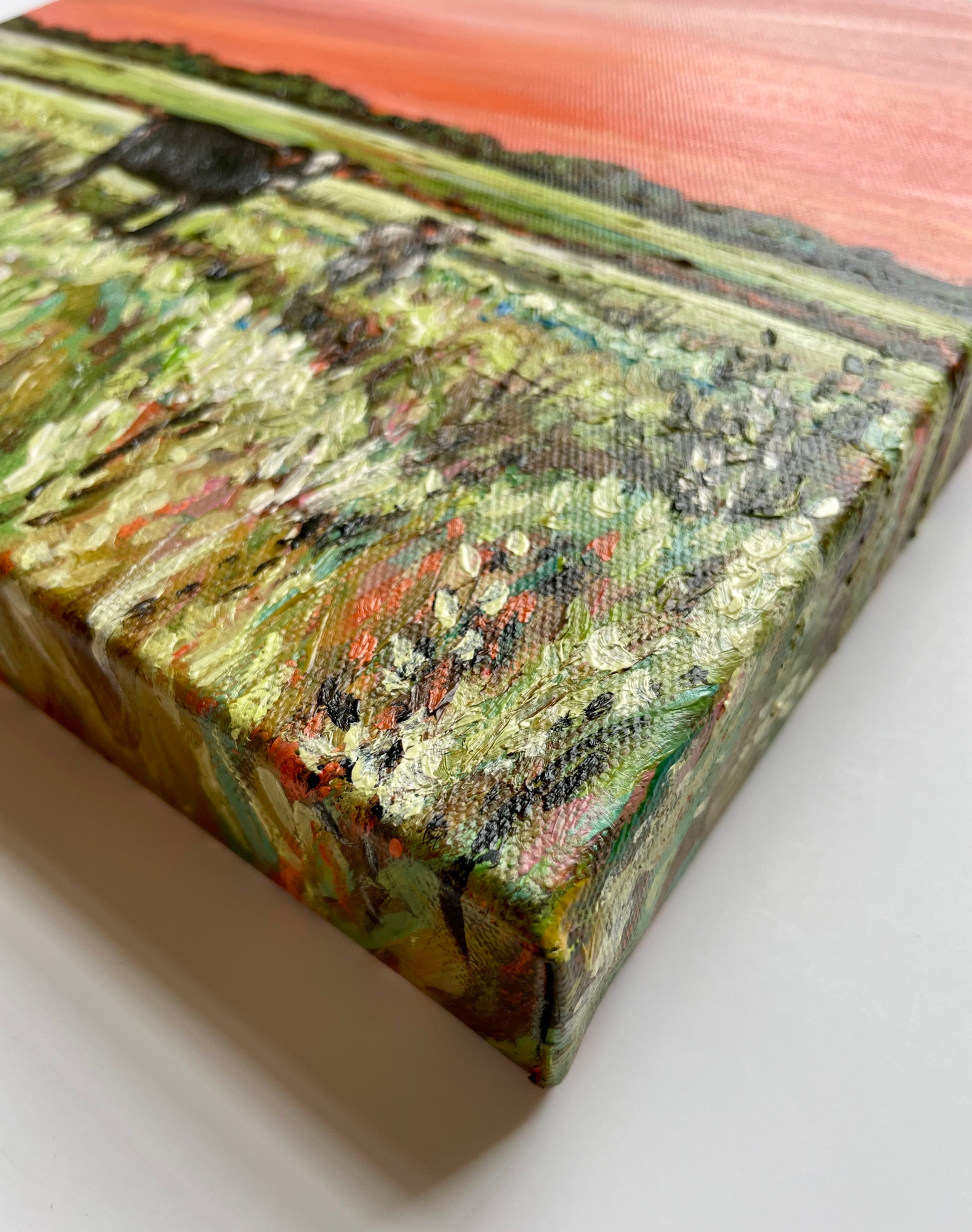 Close-up of a textured painting on a canvas with a landscape scene