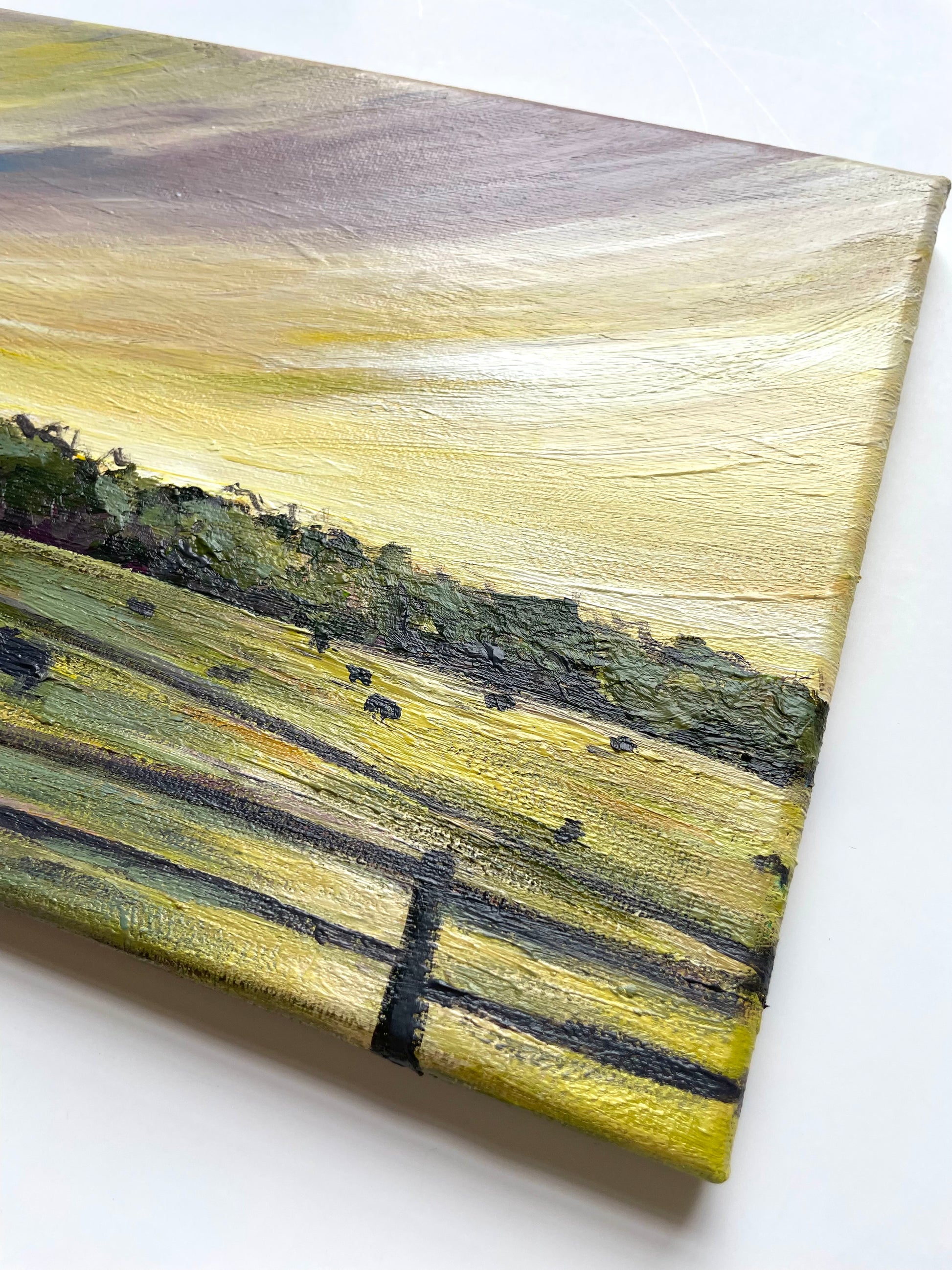 Canvas painting of a landscape with  yellow and green fields and trees with a purple and yellow sunset 
