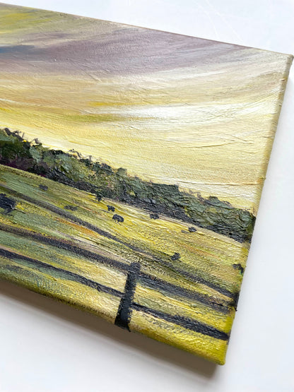 Canvas painting of a landscape with  yellow and green fields and trees with a purple and yellow sunset 
